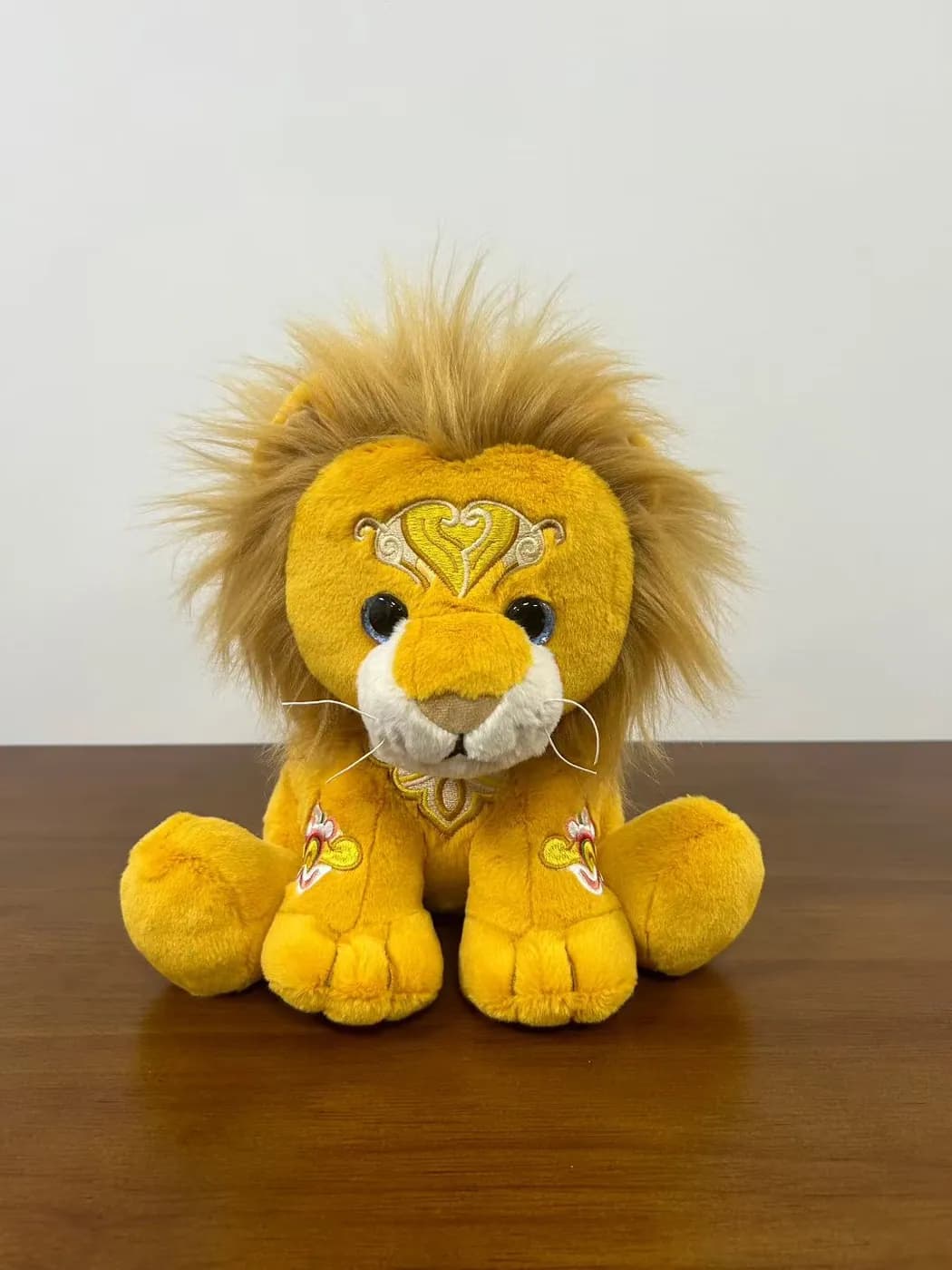 Golden lion plush toy with a long-pile mane and a metal medallion