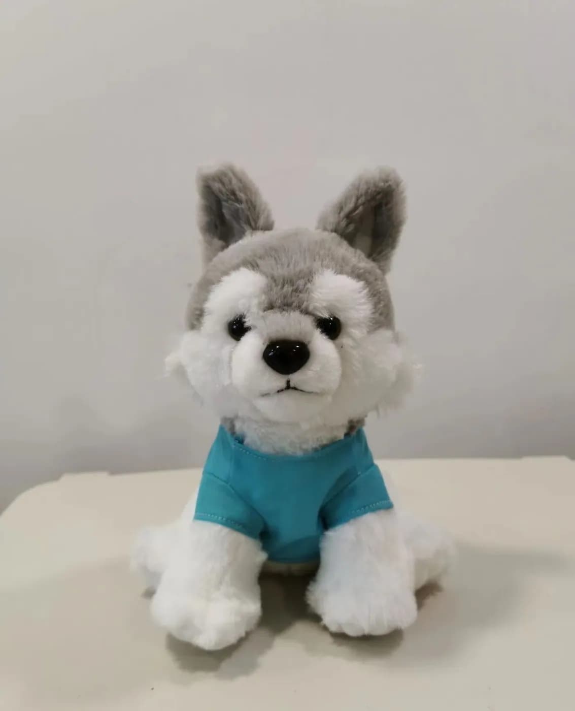 Wolf pup plush toy wearing a teal knitted top