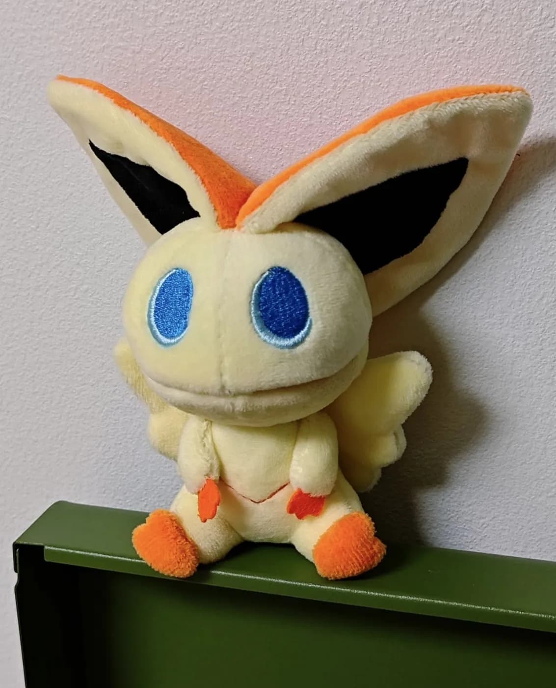 Yellow long-eared character plush standing on a shelf edge