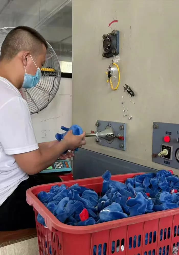 Operator filling plush bodies at the stuffing station