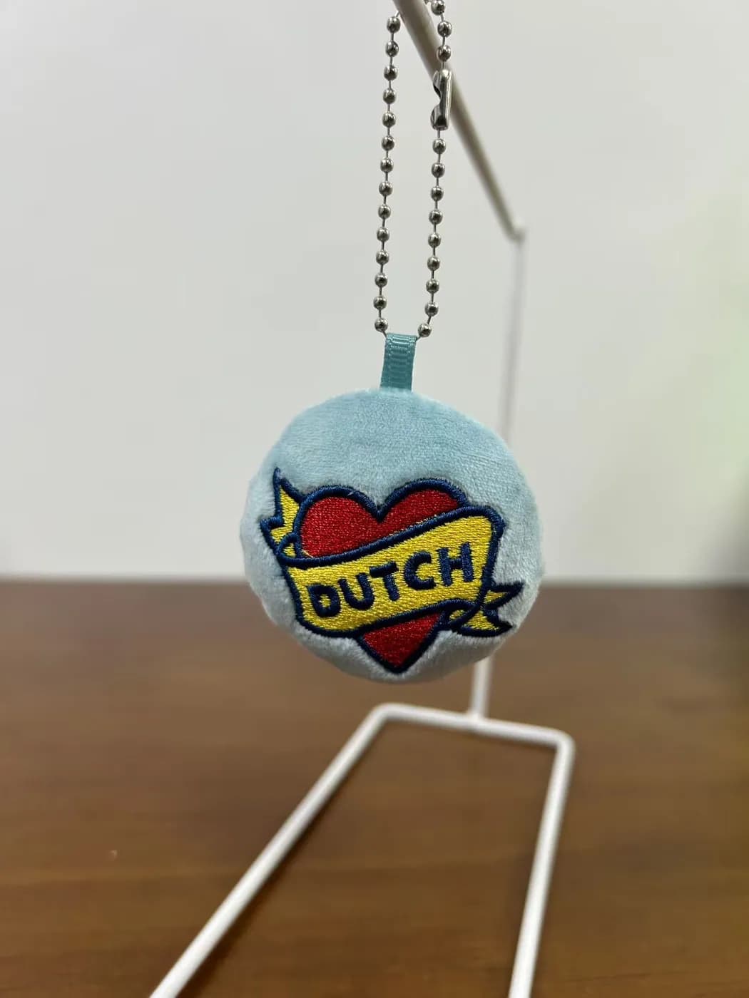 Round plush badge charm on a ball chain with a printed heart motif