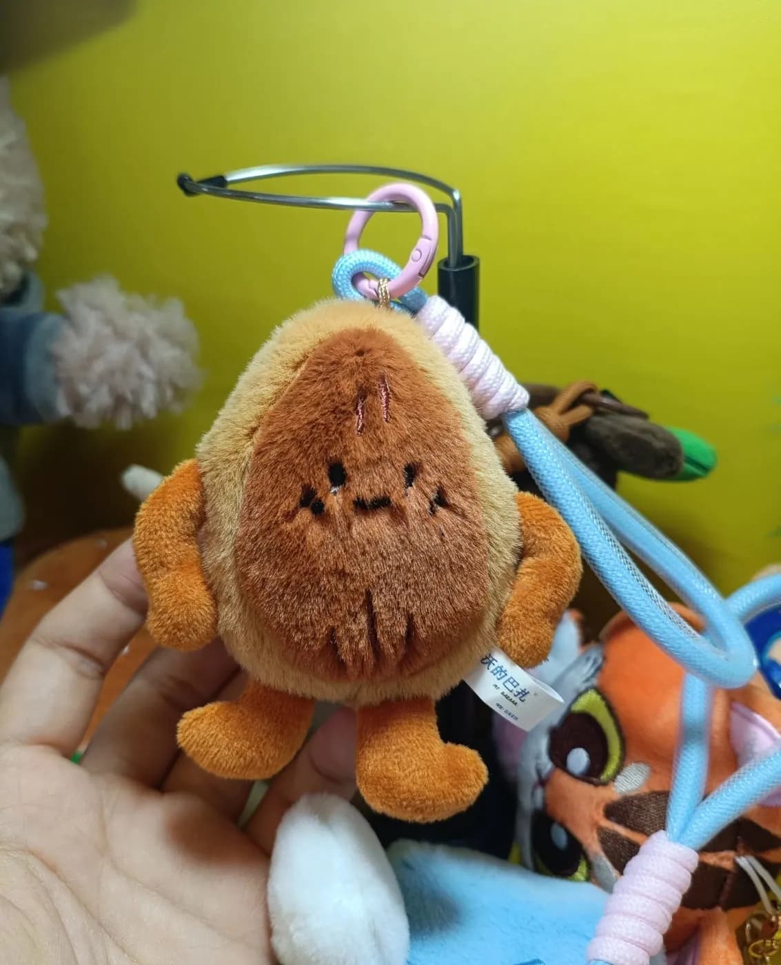 Monkey plush charm clipped to a branded carabiner strap