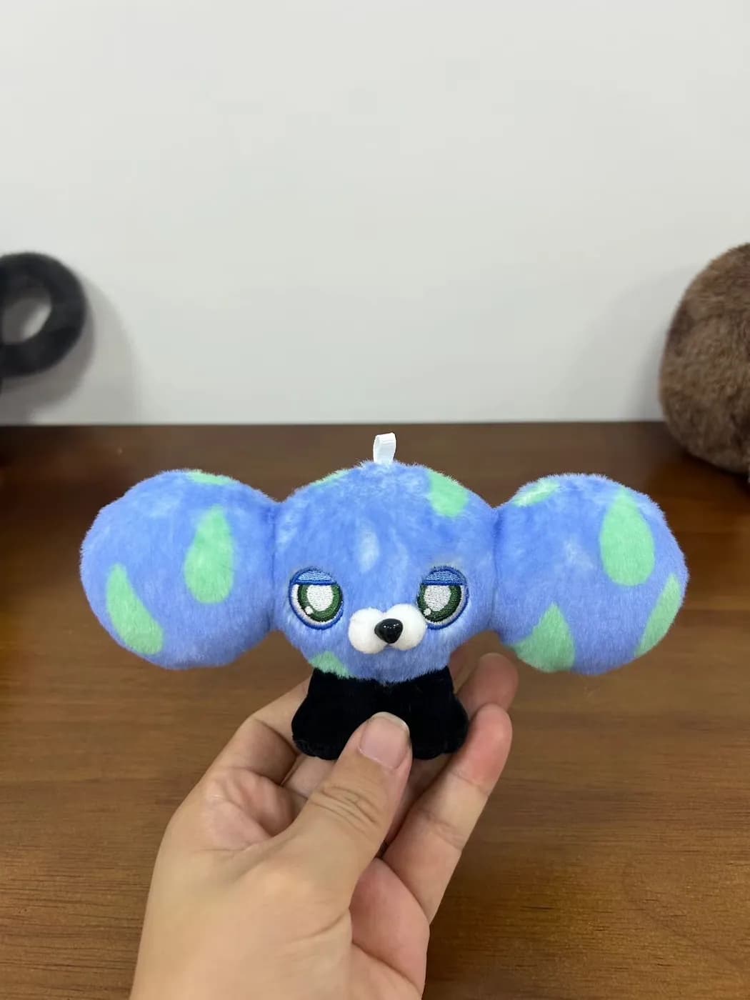 Globe plush charm with an embroidered koala face