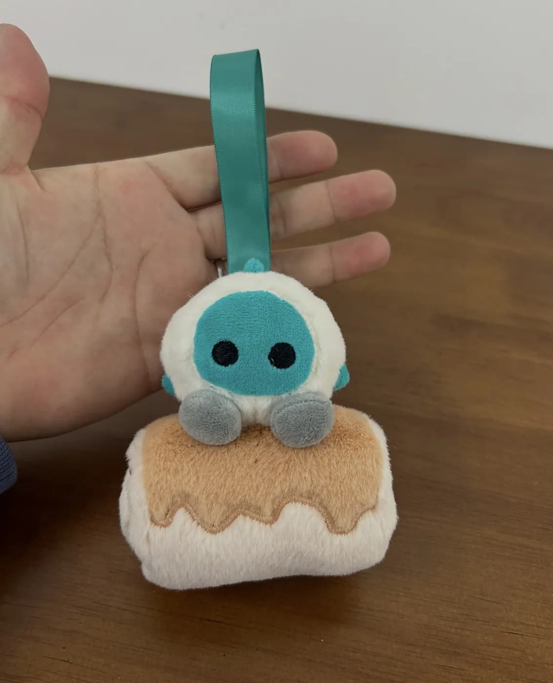 Pudding plush keychain with a ribbon strap and appliqué face