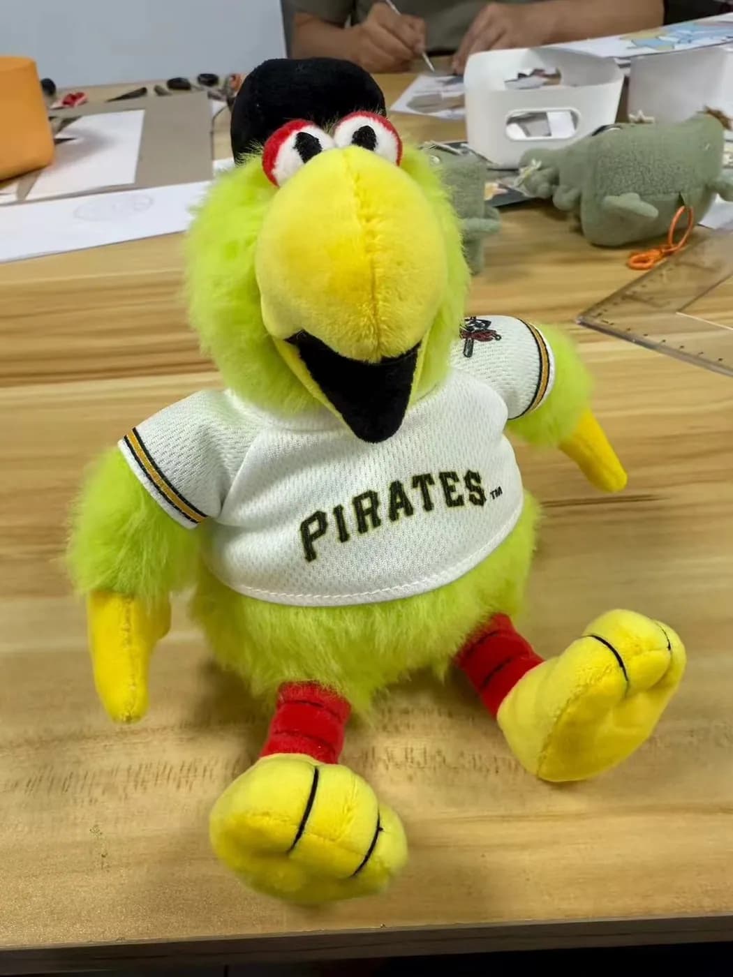 Parrot mascot plush in a baseball jersey with embroidered lettering