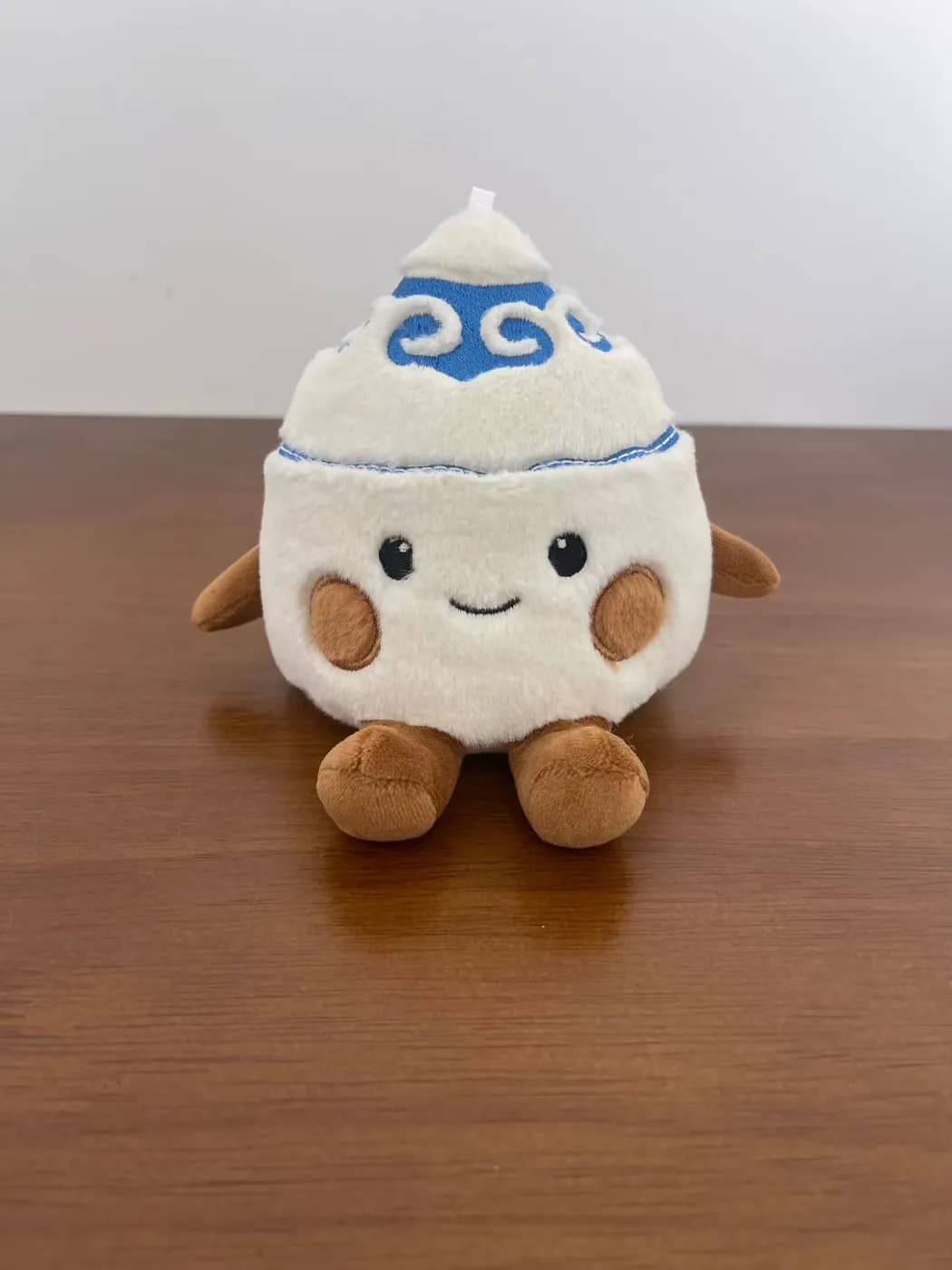 White bun character plush with an embroidered blue swirl cap