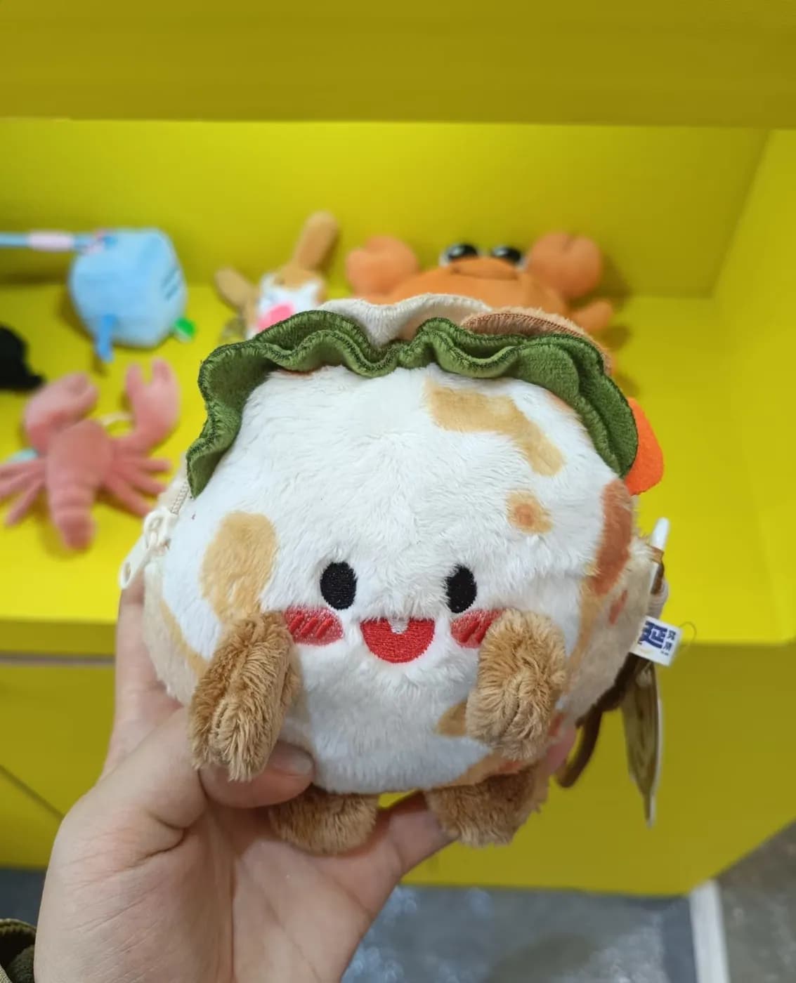 Taco plush charm with layered fabric fillings and a hangtag